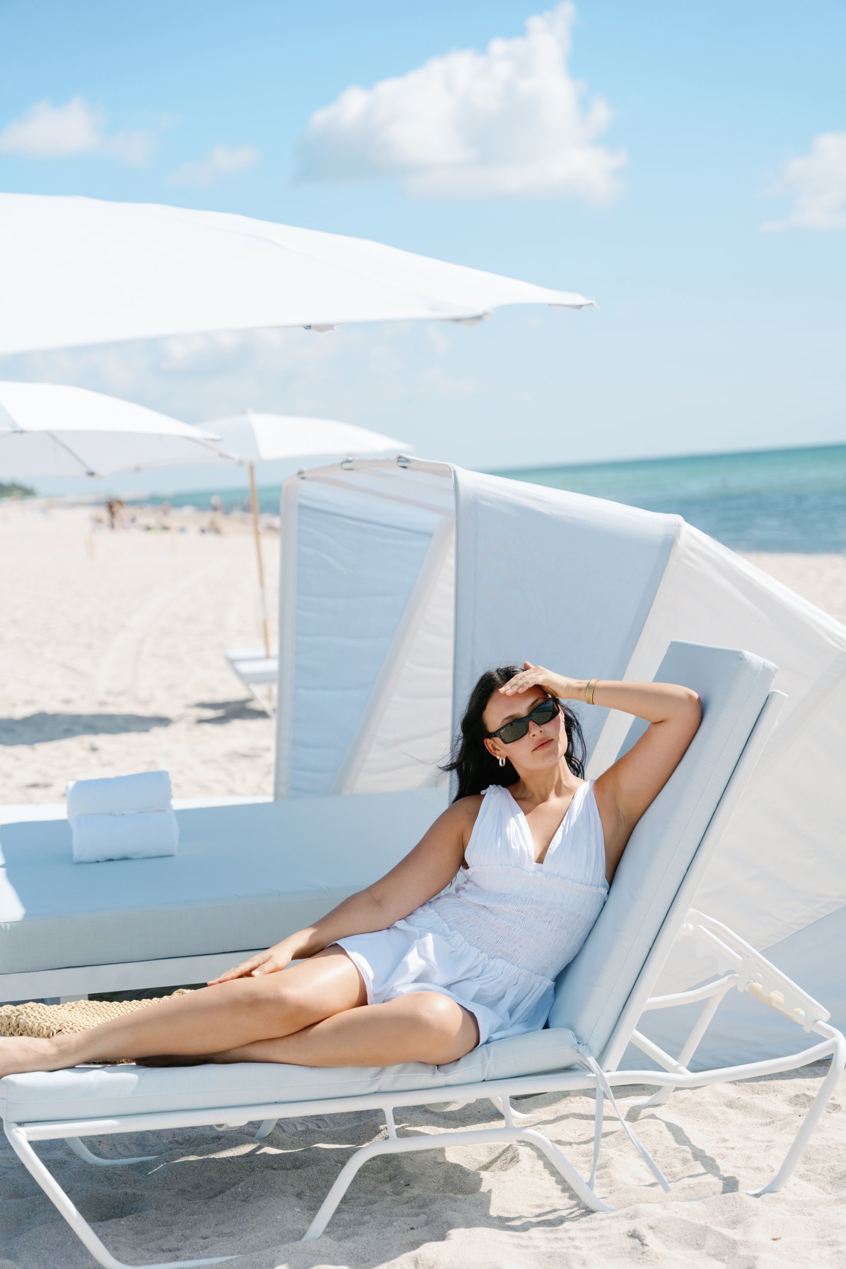 Guest on a lounge chair beneath white umbrellas